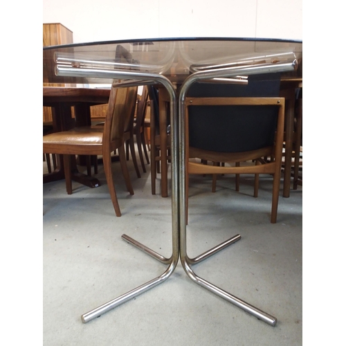 87 - A mid 20th century oval smoked glass top table on steel base, 71cm high x 124cm long x 91cm deep