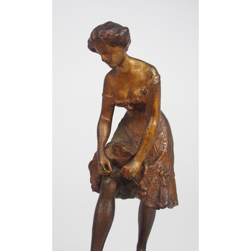 2209 - IN THE STYLE OF FRANZ BERGMANA cold painted bronze figure of a woman in petticoats, tying her stocki... 