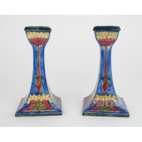2223 - A PAIR OF GEORGE CARTLIDGE FOR MORRISWARE CANDLESTICKSwith tube lined stylised decoration of seed he... 