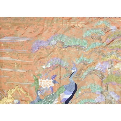 2407 -  A CHINESE SILK PANELwoven with a peacock in a garden and beneath pine, within a machine woven borde... 