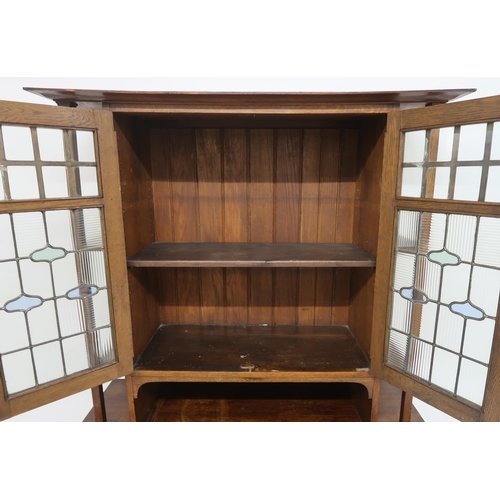 2017 - AN OAK ARTS & CRAFTS BOOKCASEwith shaped cornice over pair of central leaded stained glass doors... 
