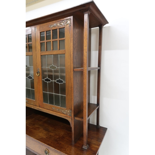 2017 - AN OAK ARTS & CRAFTS BOOKCASEwith shaped cornice over pair of central leaded stained glass doors... 