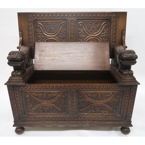 2045 - AN EARLY 20TH CENTURY CARVED OAK MONKS BENCHcarved hinged top over carved lion arms flanking central... 