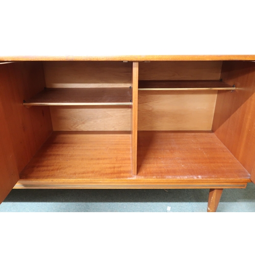 129 - A mid 20th century teak sideboard with pair of cabinet doors alongside three drawers on tapering sup... 