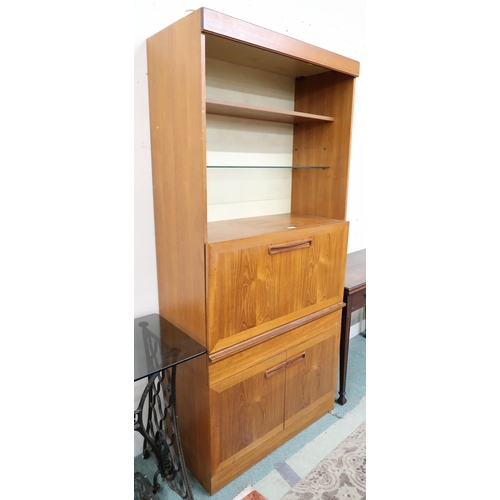 131 - A mid 20th century teak drinks cabinet with two open shelves over fall front compartment over single... 