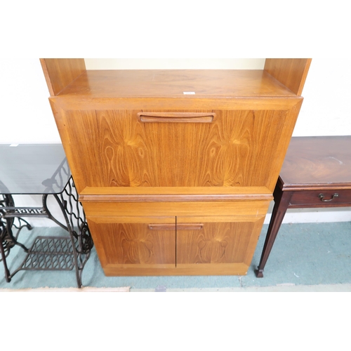 131 - A mid 20th century teak drinks cabinet with two open shelves over fall front compartment over single... 