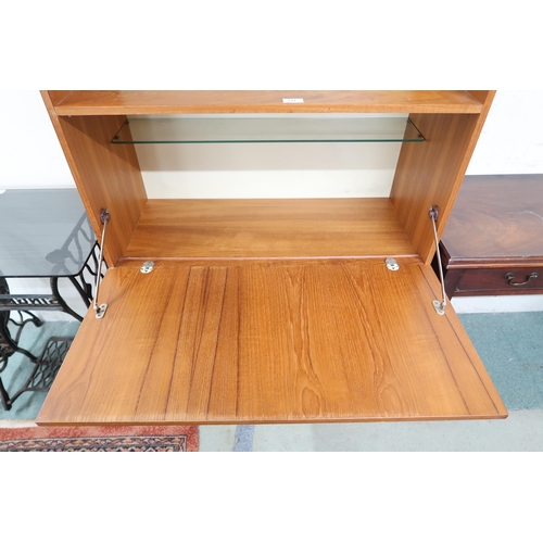 131 - A mid 20th century teak drinks cabinet with two open shelves over fall front compartment over single... 