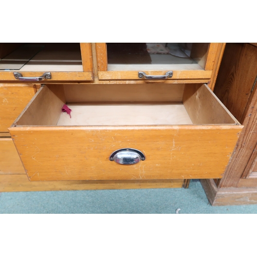 166 - An early 20th century blonde oak haberdashery cabinet with twenty four short glass front drawers ove... 