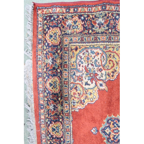 209 - A red ground Keshan style rug with beige central medallion, matching spandrels and multicoloured bor... 