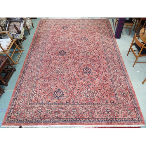 97 - A large machine woven terracotta ground rug with allover floral/foliate design with flower head bord... 