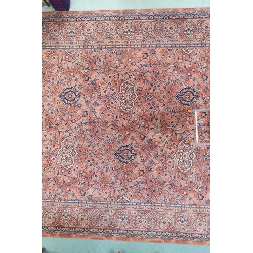 97 - A large machine woven terracotta ground rug with allover floral/foliate design with flower head bord... 