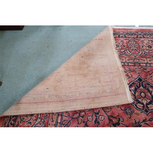 97 - A large machine woven terracotta ground rug with allover floral/foliate design with flower head bord... 