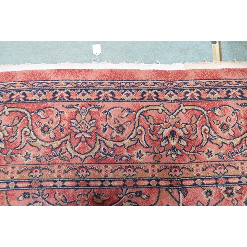 97 - A large machine woven terracotta ground rug with allover floral/foliate design with flower head bord... 