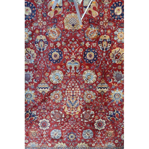 98 - A red ground Persian style rug with allover flowerhead design and flowerhead border, 352cm long x 24... 