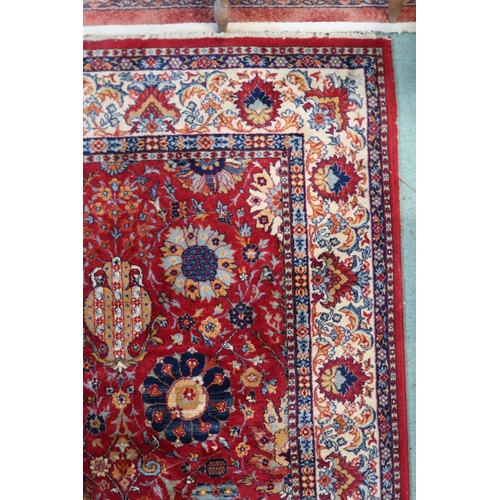 98 - A red ground Persian style rug with allover flowerhead design and flowerhead border, 352cm long x 24... 