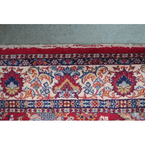 98 - A red ground Persian style rug with allover flowerhead design and flowerhead border, 352cm long x 24... 