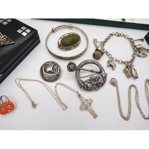 894 - A silver Tara style brooch, a Robert Allison Viking longship brooch, a silver charm bracelet with se... 