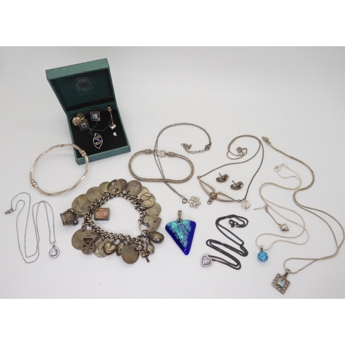 901 - A silvercharm bracelet with attached silver and white metal charms and coins, a silver bangle, and i... 