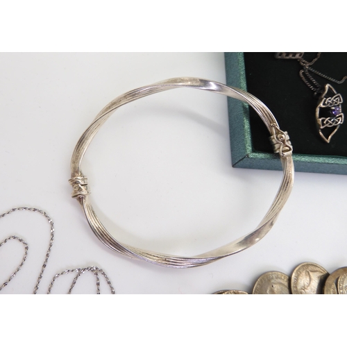 901 - A silvercharm bracelet with attached silver and white metal charms and coins, a silver bangle, and i... 