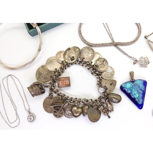 901 - A silvercharm bracelet with attached silver and white metal charms and coins, a silver bangle, and i... 