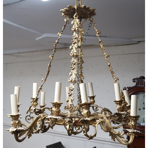 24A - An early 20th century gilt Rococo revival multibranch chandelier with brass hanging chains cast in a... 