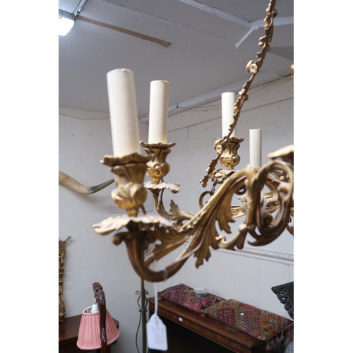 24A - An early 20th century gilt Rococo revival multibranch chandelier with brass hanging chains cast in a... 