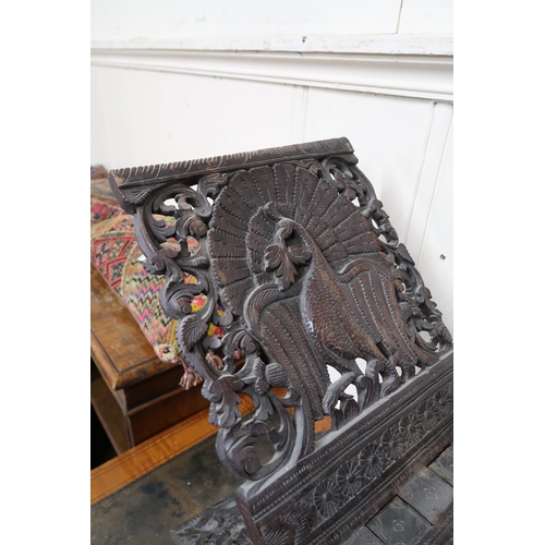 25 - An early 20th century Burmese style folding stool extensively carved with peacocks, a carved game bo... 