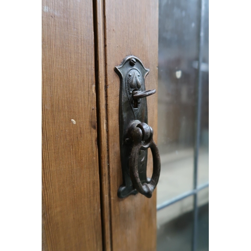 71 - An early 20th century oak arts and crafts style glazed bookcase with pair of leaded glass doors cent... 