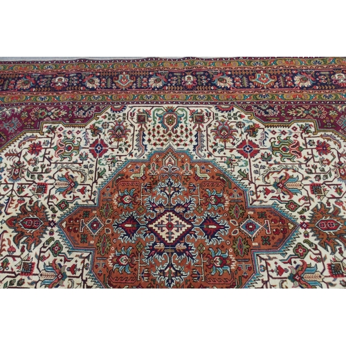 2130 - A CREAM GROUND TABRIZ RUGwith terracotta central medallion, red spandrels and dark blue flower head ... 