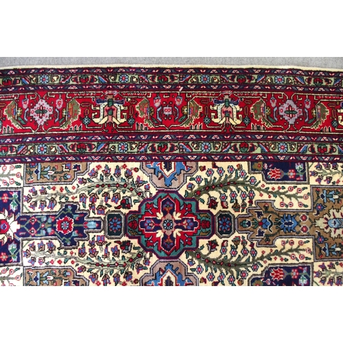 2135 - A CREAM GROUND TABRIZ RUGwith all-over multicoloured floral geometric design and red flower head bor... 