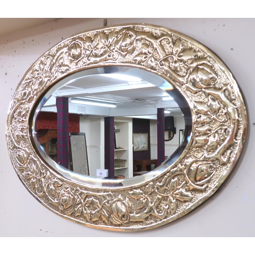 36 - An early 20th century British brass framed oval wall mirror with frame embossed with rose heads and ... 