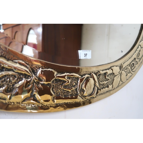 37 - An early 20th century British brass framed oval wall mirror with frame embossed with flowerheads and... 