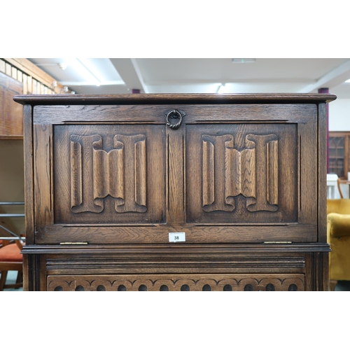 38 - A 20th century oak linen fold drinks cabinet with fall front drinks compartment over single drawer o... 