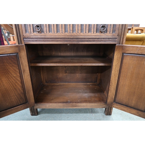 38 - A 20th century oak linen fold drinks cabinet with fall front drinks compartment over single drawer o... 