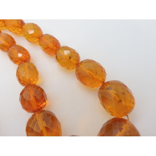 667 - A string of amber coloured beads, weight 94.1gms approx, together with a silver Mackintosh style pen... 