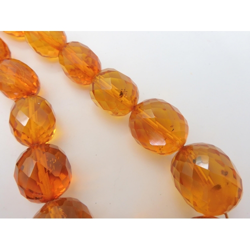 667 - A string of amber coloured beads, weight 94.1gms approx, together with a silver Mackintosh style pen... 