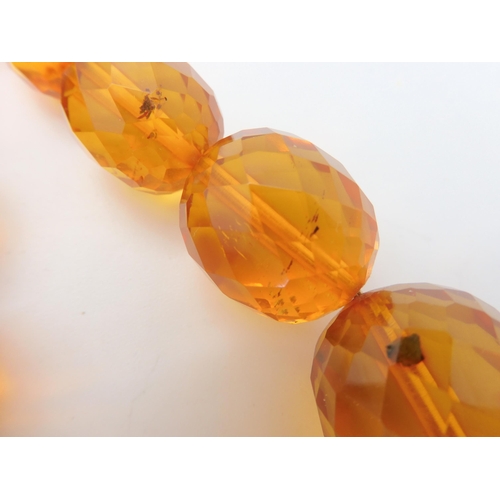 667 - A string of amber coloured beads, weight 94.1gms approx, together with a silver Mackintosh style pen... 