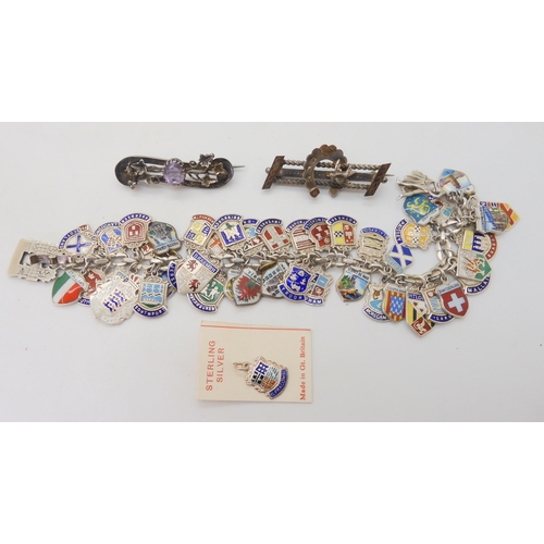 677 - An extensive silver and enamel place name charm bracelet, with two Victorian white metal brooches