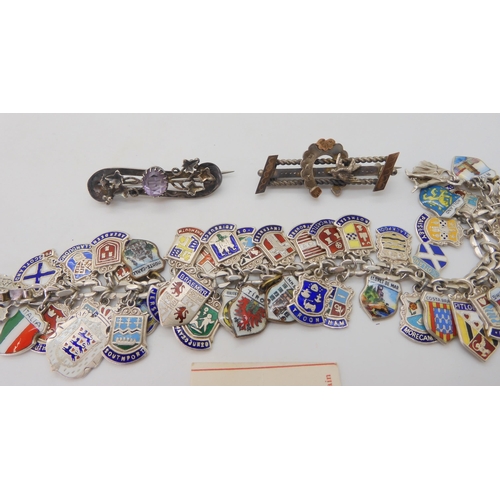 677 - An extensive silver and enamel place name charm bracelet, with two Victorian white metal brooches