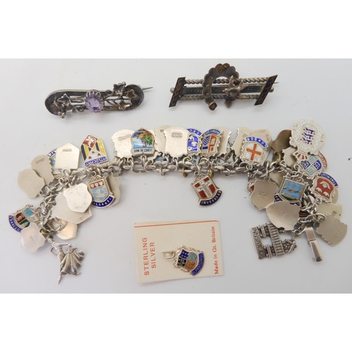 677 - An extensive silver and enamel place name charm bracelet, with two Victorian white metal brooches