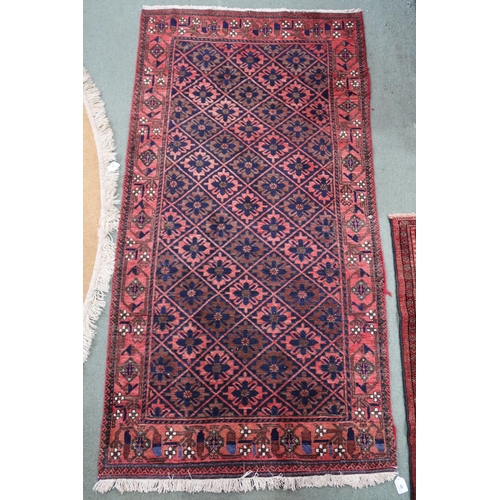 68 - A pink ground balouch rug with allover flower head pattern ground and geometric floral border, 179cm... 