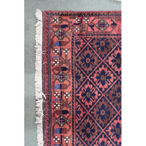 68 - A pink ground balouch rug with allover flower head pattern ground and geometric floral border, 179cm... 