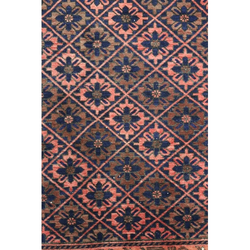 68 - A pink ground balouch rug with allover flower head pattern ground and geometric floral border, 179cm... 