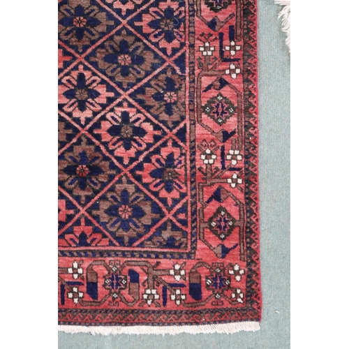 68 - A pink ground balouch rug with allover flower head pattern ground and geometric floral border, 179cm... 