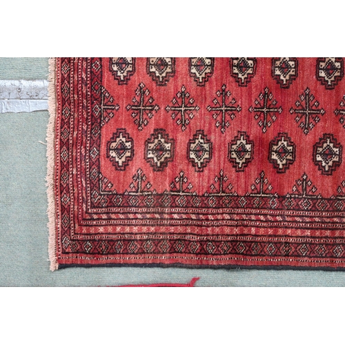 69 - A red ground bokhara rug with all over lozenge design and multiple borders, 105cm long x 83cm wide