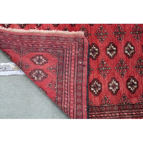 69 - A red ground bokhara rug with all over lozenge design and multiple borders, 105cm long x 83cm wide