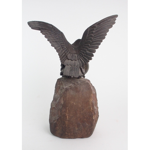 2167 - A BRONZE AND STONE WATCH HOLDER modelled as an eagle perched on a rock, holding a German made bullse... 