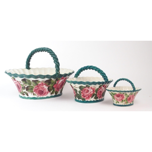 2176 - THREE WEMYSS GRADUATED BASKETS each of oval form and painted with cabbage roses, with green rope twi... 