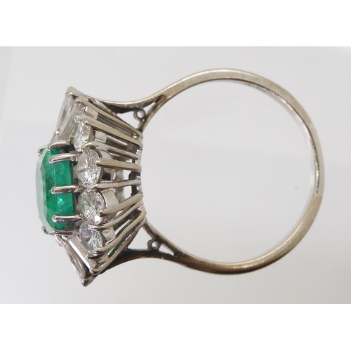 2747 - AN EMERALD & DIAMOND CLUSTER RINGset with a step cut emerald of approx 8.95mm x 8.33mm x 4.6mm i... 