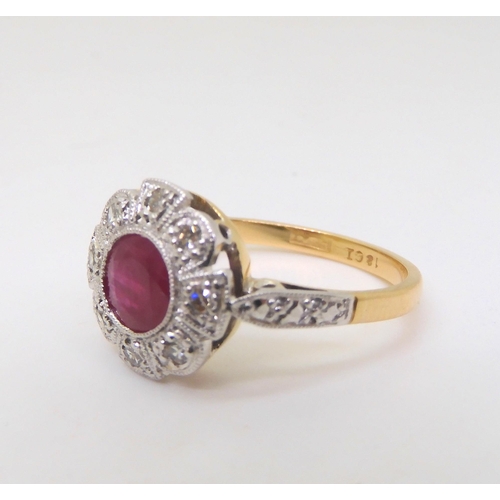 2825 - A VINTAGE RUBY AND DIAMOND RINGset with a central ruby surrounded with eight cut diamonds, to a flow... 